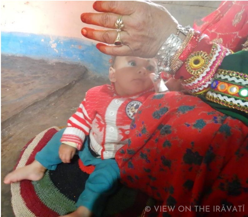 baby looking up at highly ornamented hand.
