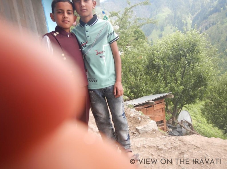 Two gaddi boys posing for a picture obscured by a fingertip