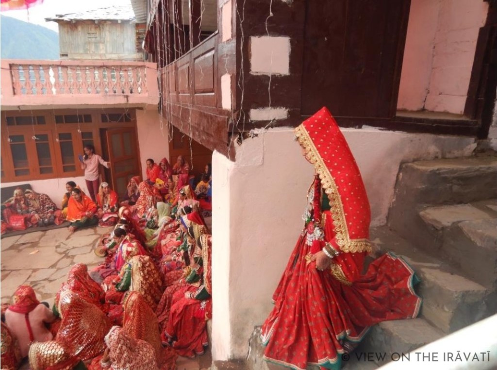 Gaddi woman in luanchari coming down stairs to join padhua ceremony.